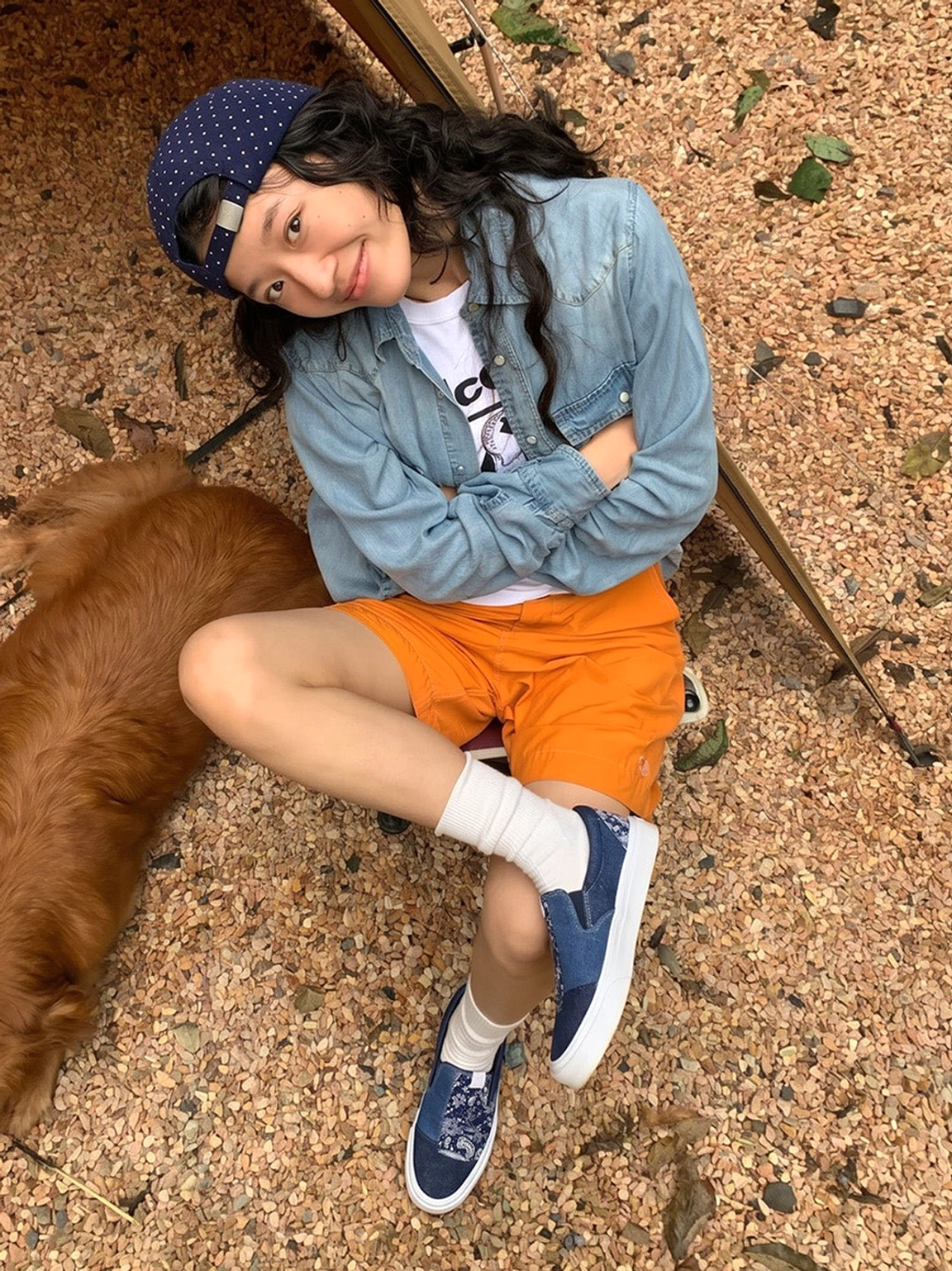 Female model styling blue paisley patchwork slip-on sneakers with a casual denim outfit at an outdoor campsite