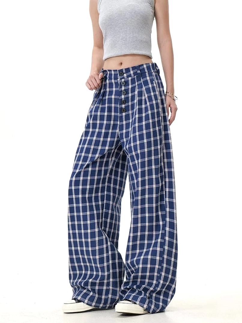Blue plaid high-waisted wide-leg trousers shown from a side angle with oversized leg shape and button front