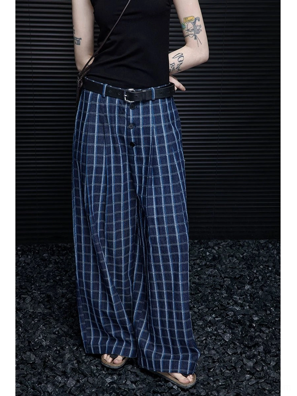 Close side view highlighting the button and zip closure, pleated waist, blue windowpane plaid fabric, and wide-leg trouser construction