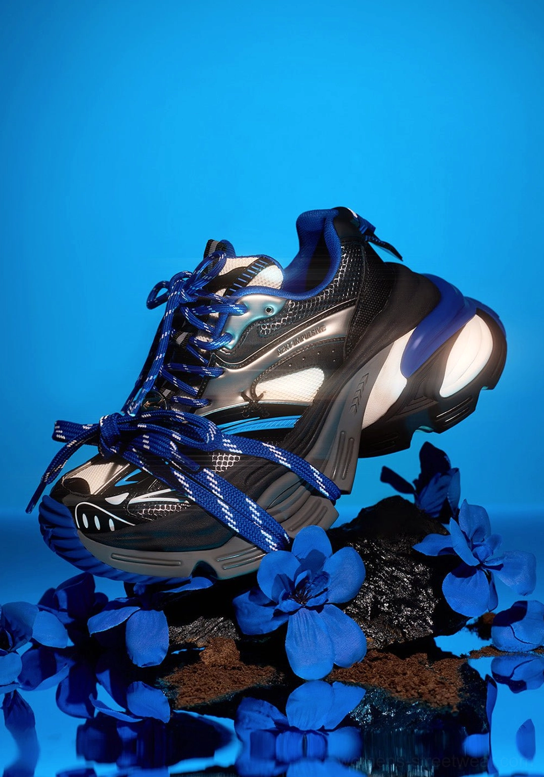 Single blue retro chunky sneaker in side profile showing the structured vamp, wrapped lace system, black and silver color blocking, and thick platform sole