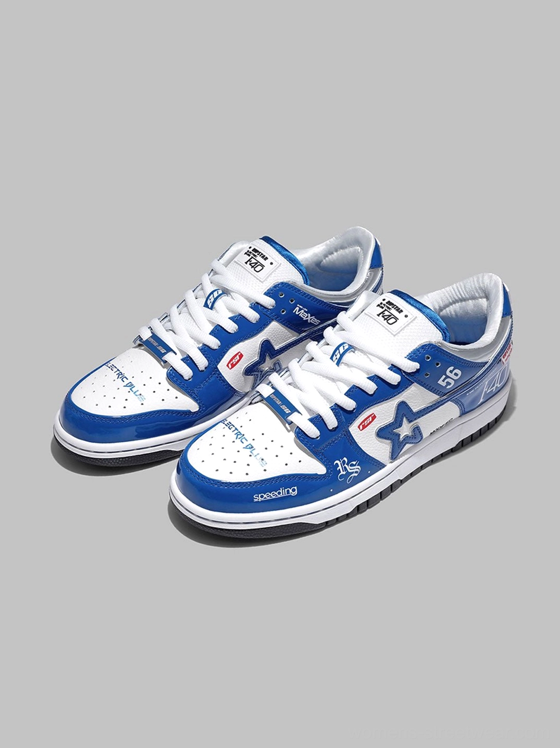Angled front view of blue retro racing skate shoes with white flat laces, glossy leather-look upper, star logo, and motorsport-inspired prints