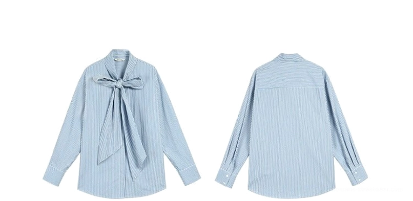Asian model wearing a blue and white striped oversized bow blouse with relaxed sleeves and a polished black clutch for modern streetwear styling
