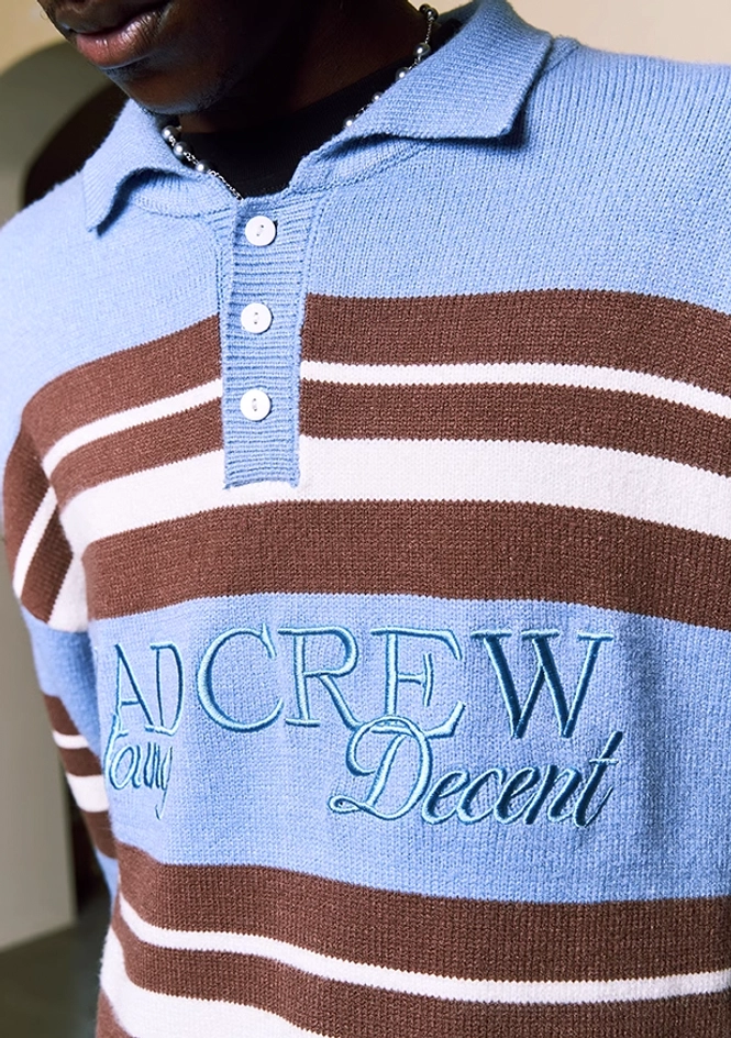Close-up of embroidered chest logo on blue striped polo collar knit sweater
