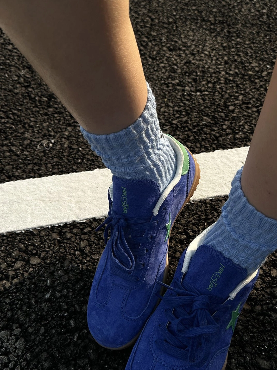 Front close-up of pair of blue suede retro streetwear sneakers showing lace-up closure toe shape and gum outsole