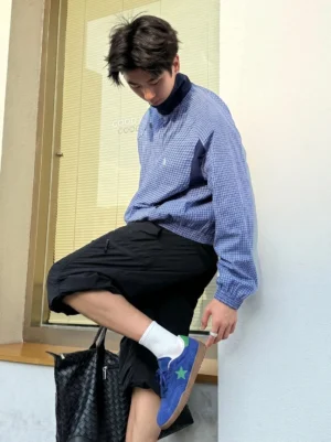 Asian male model wearing blue suede star embroidered gum sole sneakers with white crew socks and cargo shorts indoors