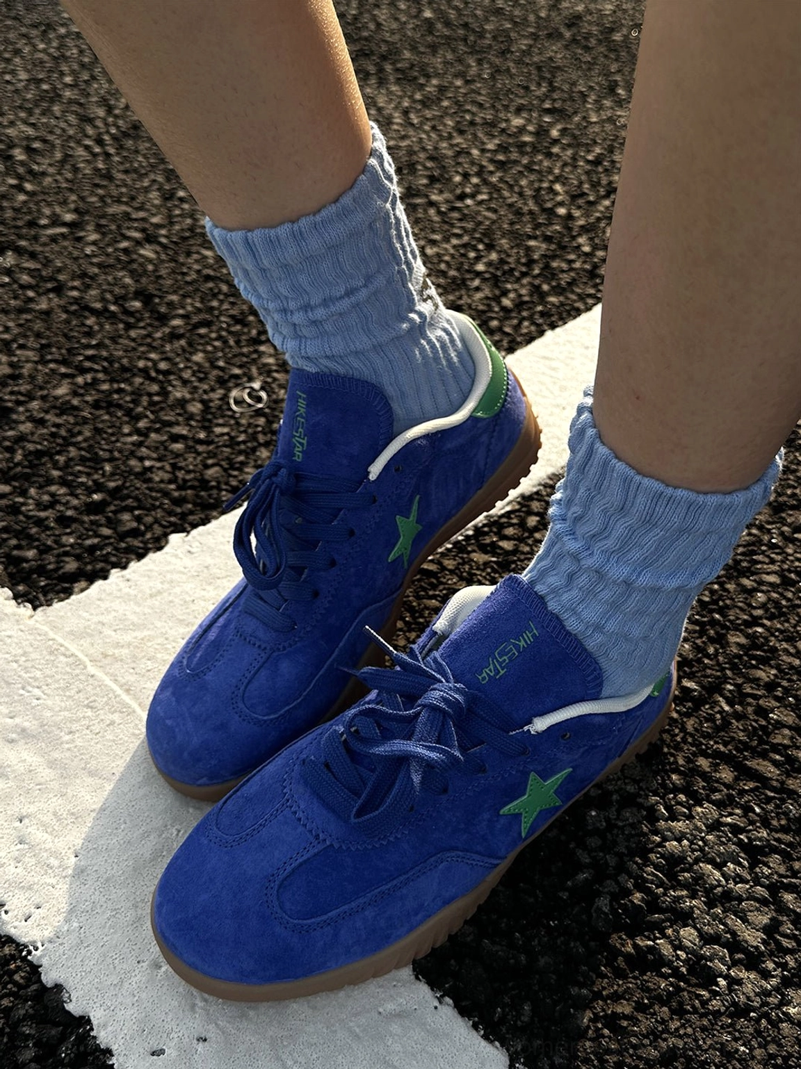 Side close-up of blue suede star embroidered gum sole sneakers worn with ribbed light blue socks