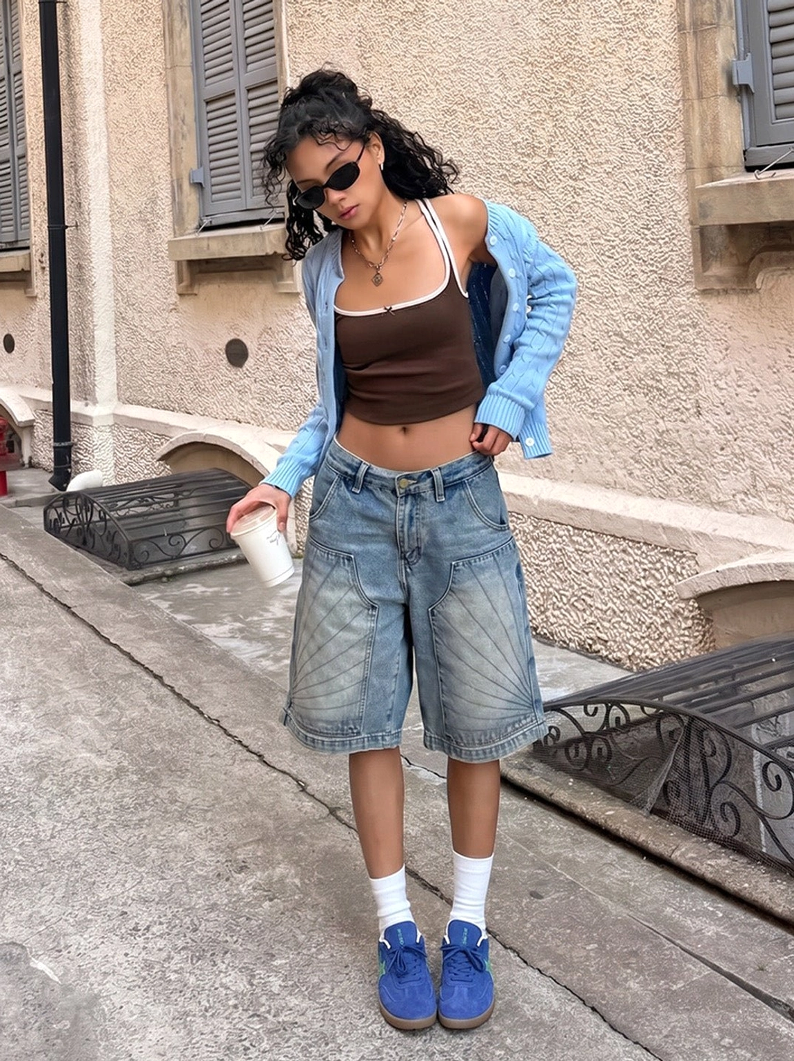 Female model wearing blue suede star embroidered gum sole sneakers on a vintage residential street