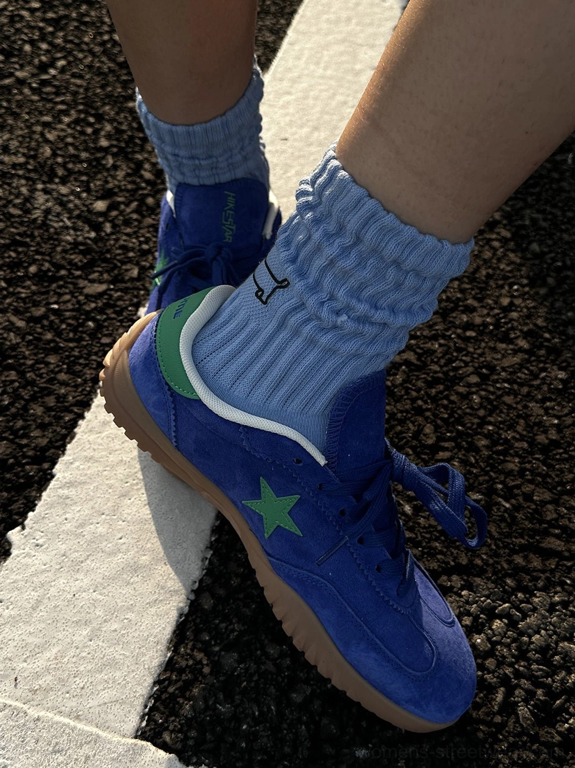 Single foot side view of blue suede star embroidered low-top sneaker with green heel accent and gum sole