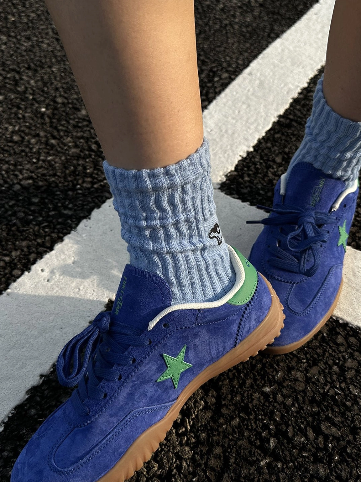 Double foot close-up of blue suede star embroidered retro sneakers highlighting heel details and gum rubber soles
