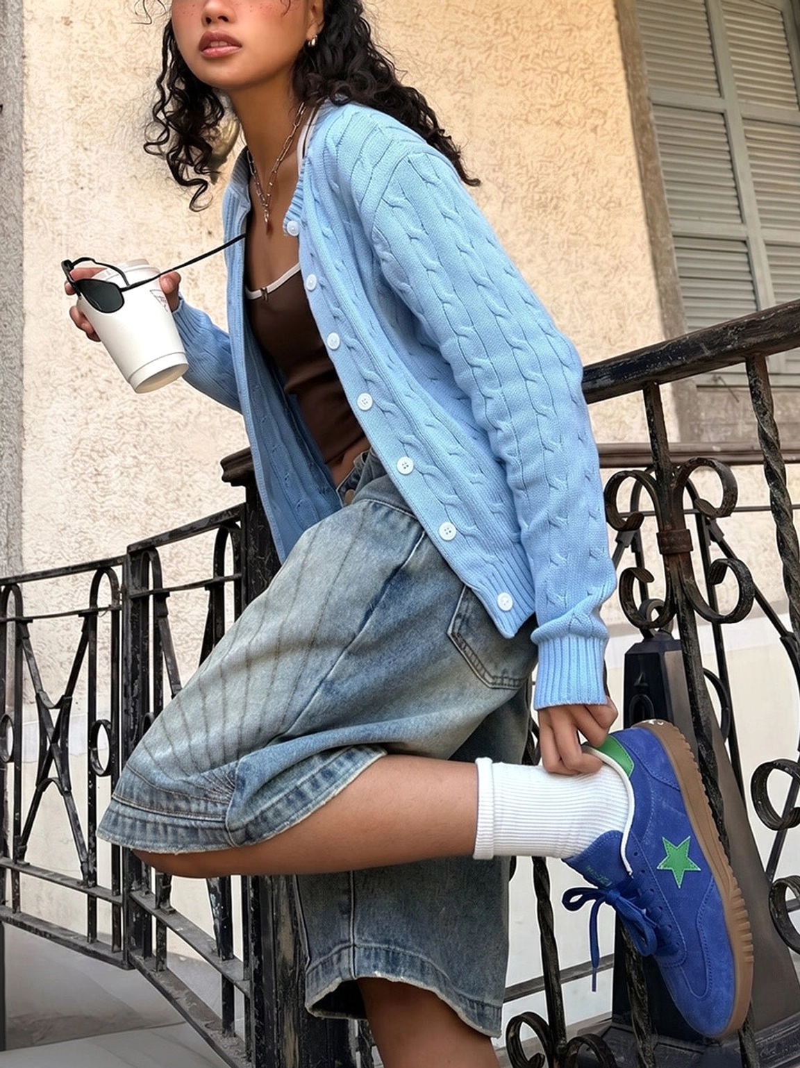 Female model styling blue suede star embroidered retro sneakers with white socks denim shorts and knit cardigan