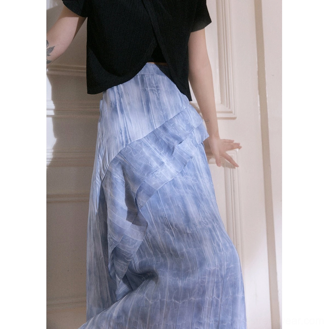 Back left close-up view of blue tie-dye ruffle cascade streetwear maxi skirt showing fluid drape and side ruffle overlay