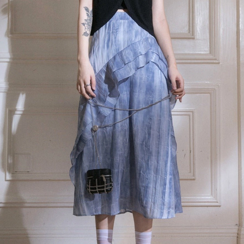 Blue tie-dye ruffle cascade streetwear maxi skirt shown in a rear three-quarter full-body look with black top and chain bag