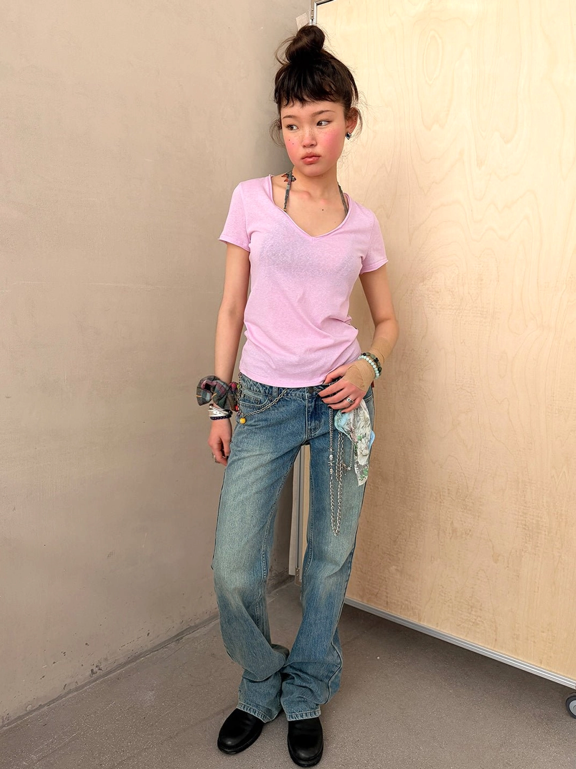 Front three-quarter styling view of blue vintage wash slim flare jeans with printed fabric accents, cropped top, and bracelets