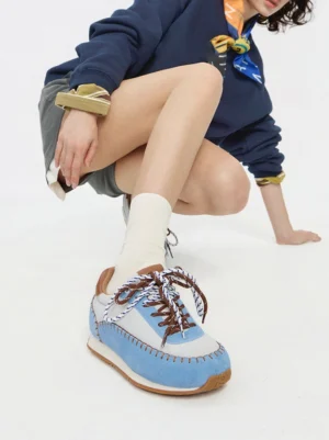 Blue and white contrast-stitch platform sneaker worn by a woman with mixed-color laces and casual streetwear styling