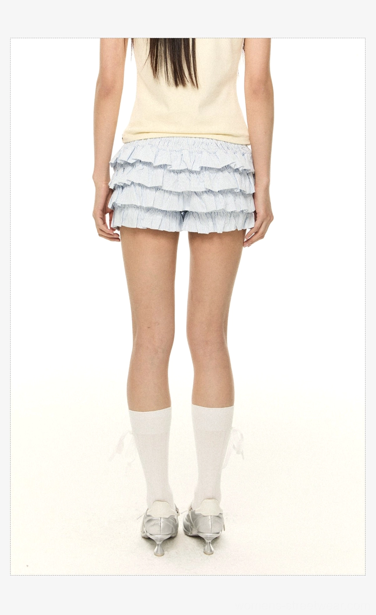 Blue and white pinstripe tiered ruffle mini shorts shown from the back with an elastic waistband, layered hem, yellow tee, socks, and silver loafers