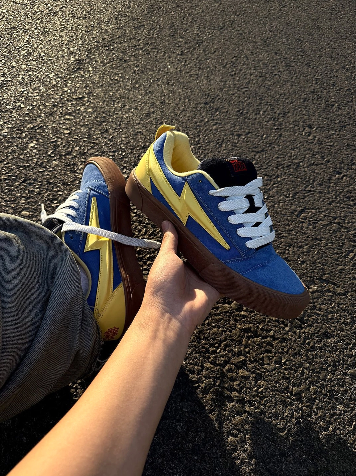 Close hand held view of blue yellow lightning bolt colorblock skate sneaker with gum rubber outsole and contrast panels