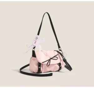 Blush pink lace bow ruched shoulder satchel with black contrast straps and ribbon pendant front three quarter view