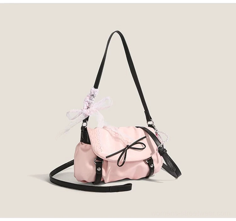 Blush pink lace bow ruched shoulder satchel with black contrast straps and ribbon pendant front three quarter view