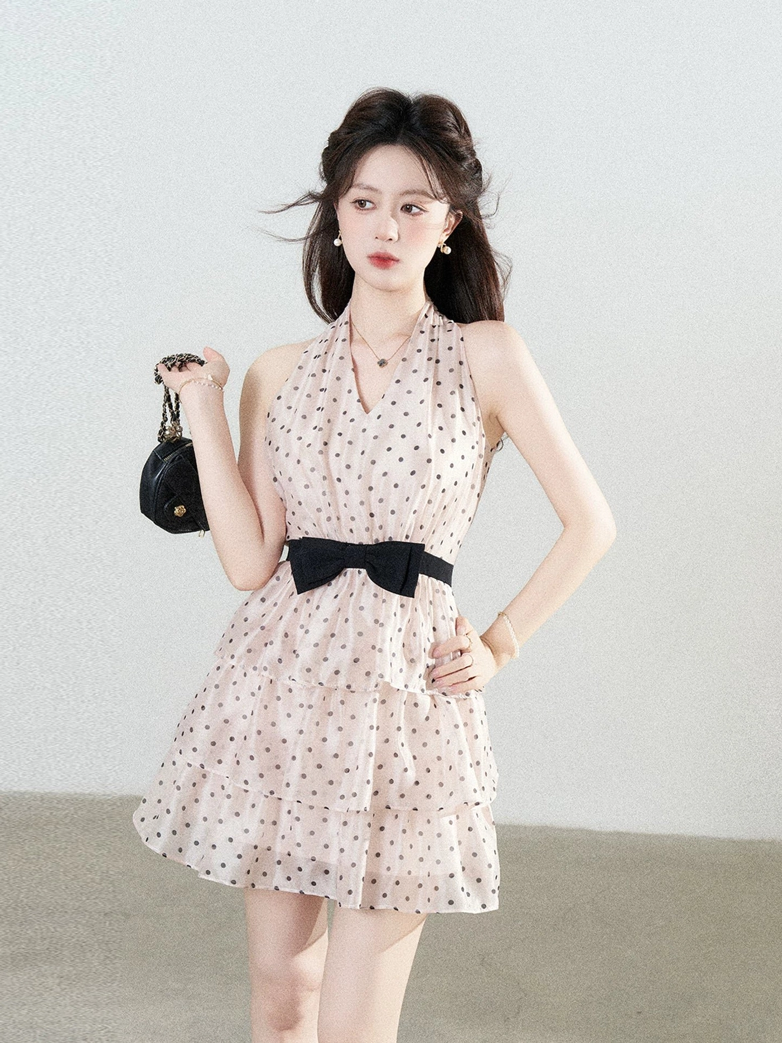 Blush pink polka dot bow halter tiered mini dress three-quarter side view with layered skirt