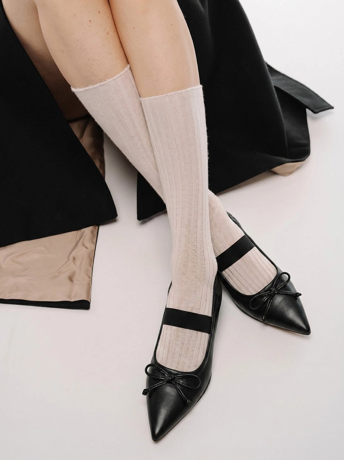 Model wearing black bow pointed-toe Mary Jane sculpted-heel mules with beige crew socks