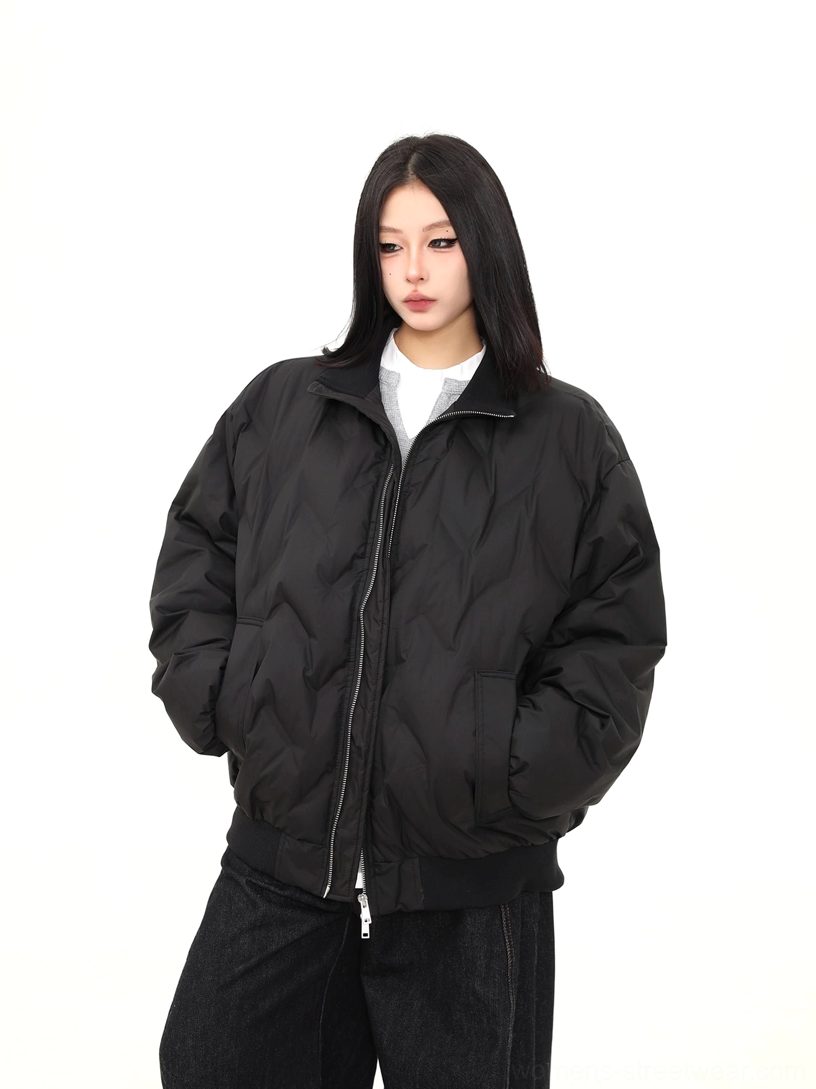 Low angle front view of a boxy oversized black puffer bomber jacket with ribbed cuffs, side pockets, and zip closure