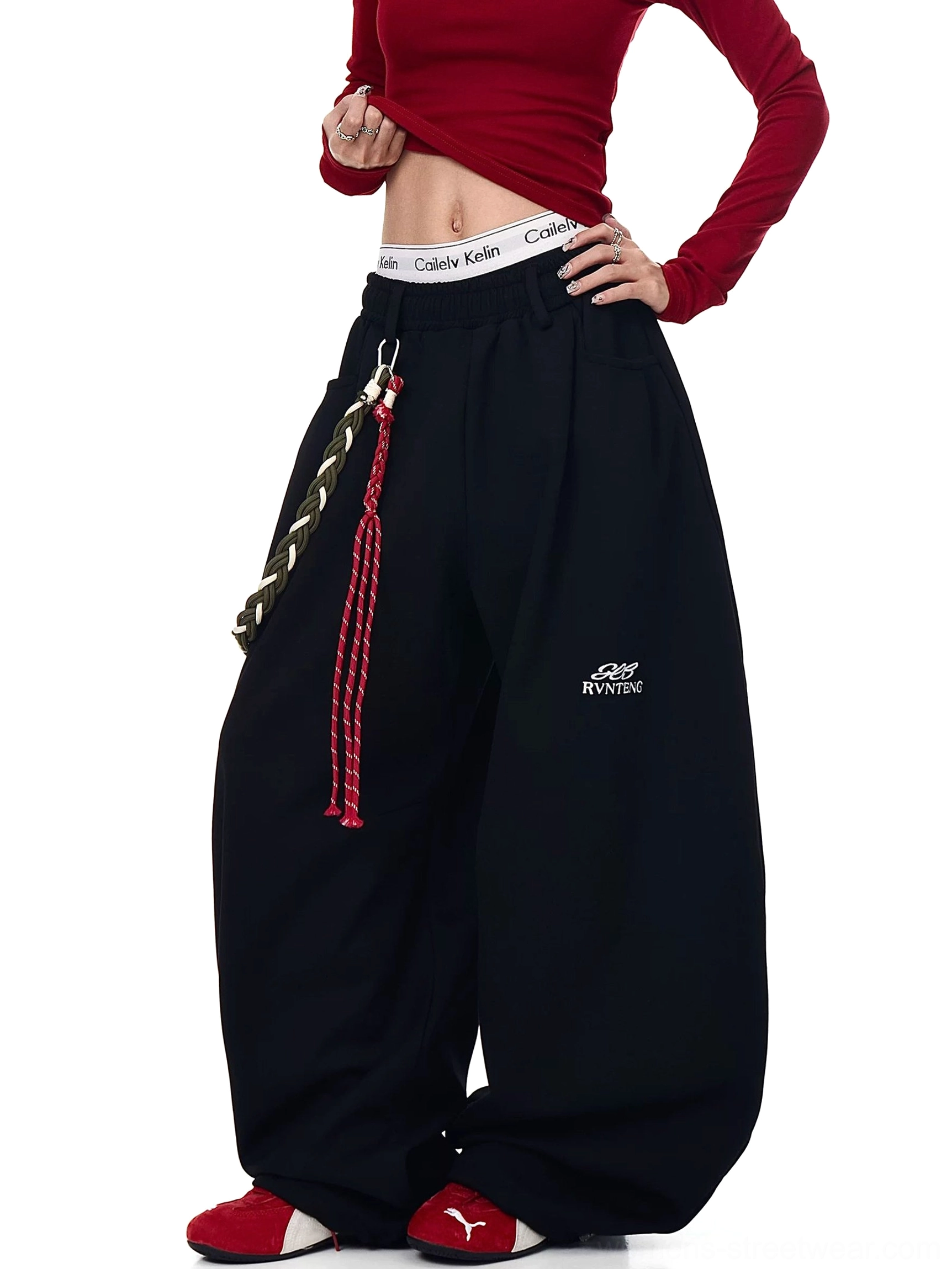 Black braided rope ultra-wide fleece streetwear track pants three-quarter side view with cropped red top and sneakers