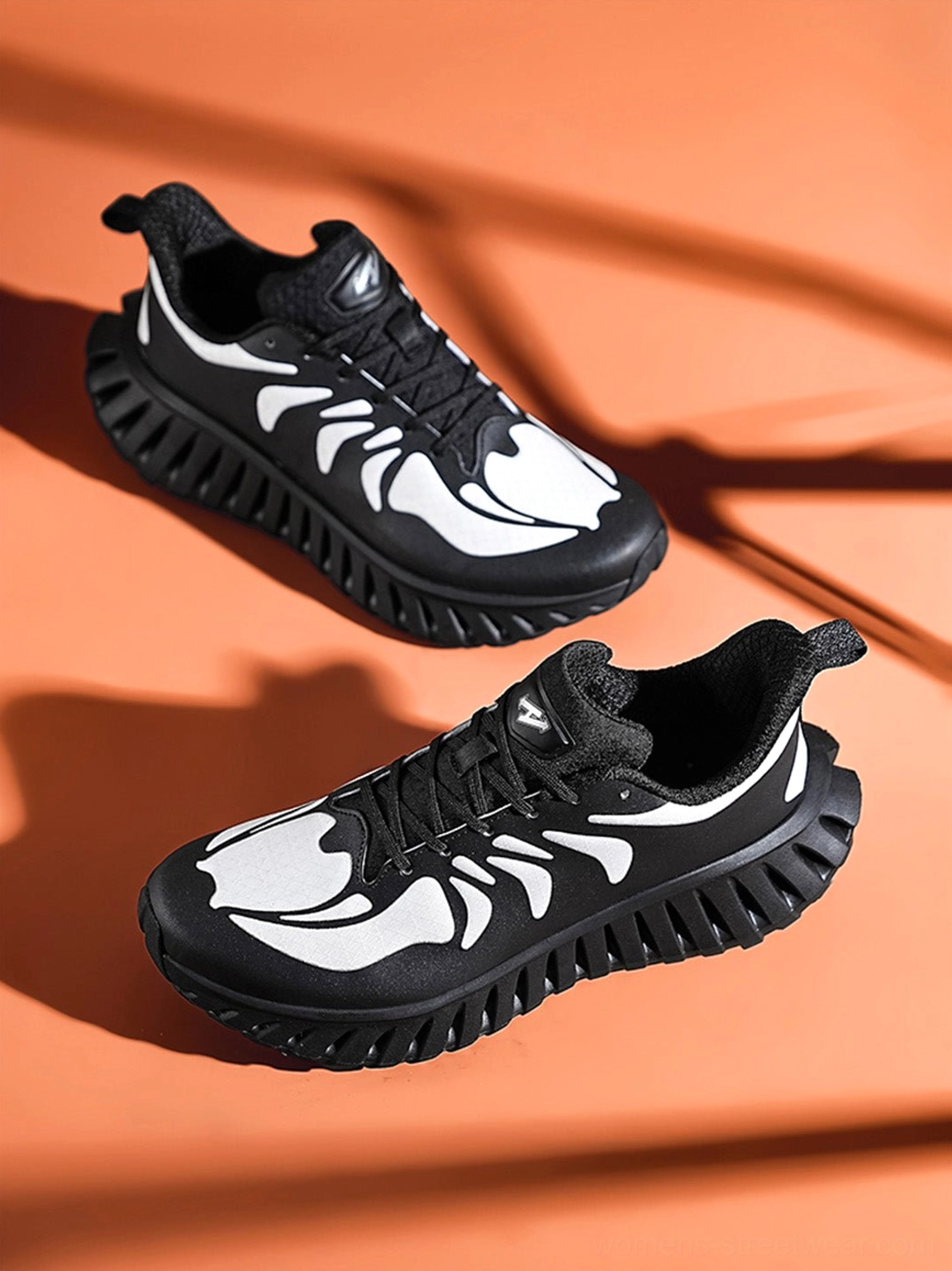 Pair of black and white skeletal-detail running sneakers shown from an overhead angle with a breathable paneled upper and rugged serrated outsole