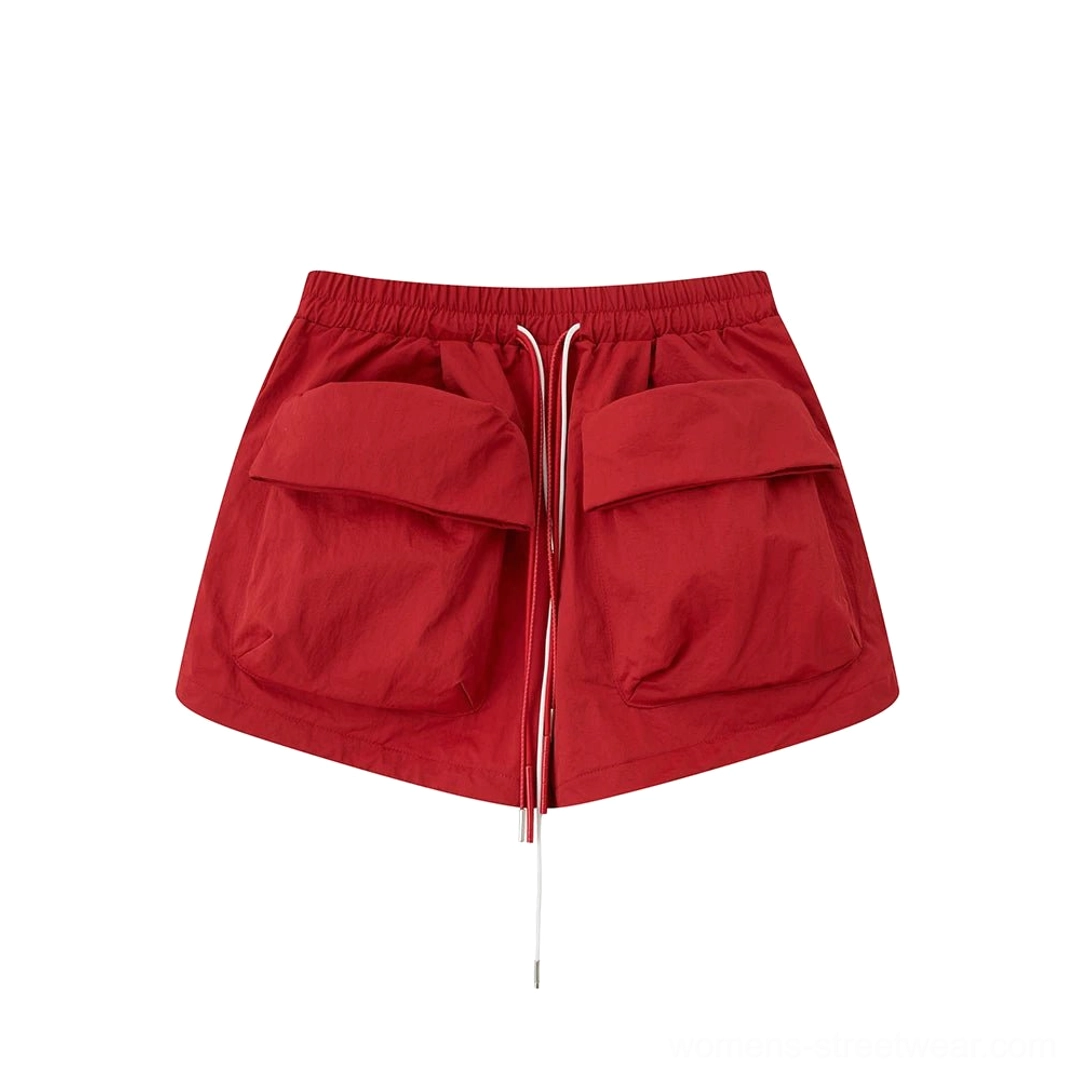 Bright red women’s cargo utility shorts flat lay with adjustable drawstring waistband, oversized flap pockets, and short streetwear silhouette