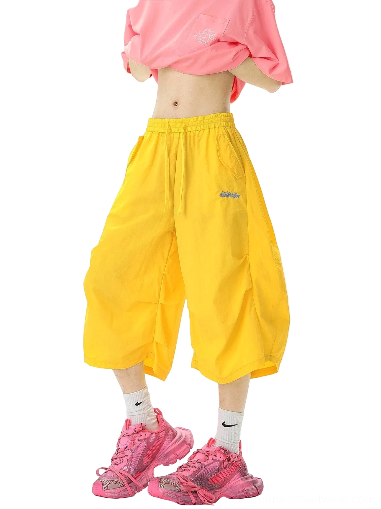 Bright yellow oversized balloon jogger shorts with lightweight matte nylon fabric, elastic drawstring waist, embroidered side badge, and bold Y2K streetwear styling