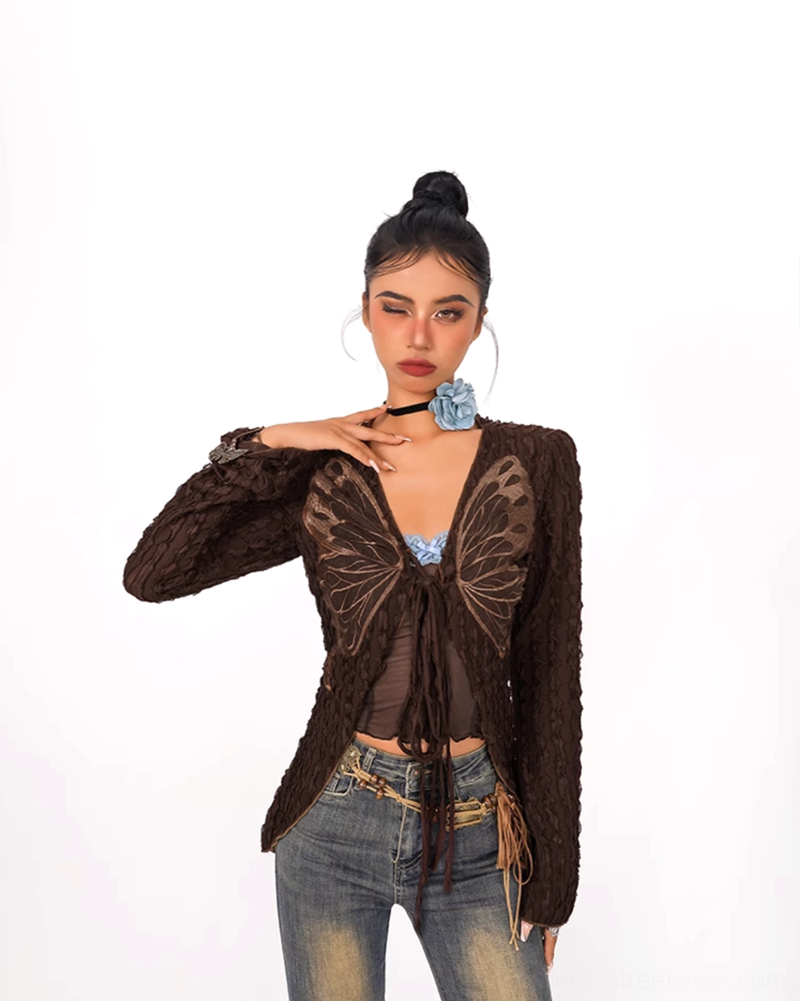 Close-up of bronze butterfly twist-front crop top layered over a blue bralette with fitted silhouette and textured fabric