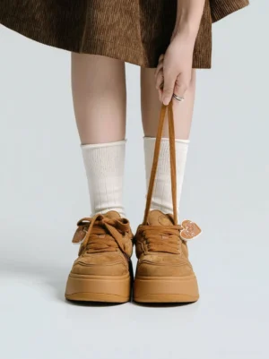Women's brown platform skate sneakers shown from the back with white crew socks and a retro corduroy skirt streetwear outfit