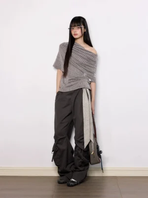 Side view of brown off-shoulder pinstripe knit top with draped asymmetric collar, embroidered star detail, and fitted Acubi silhouette