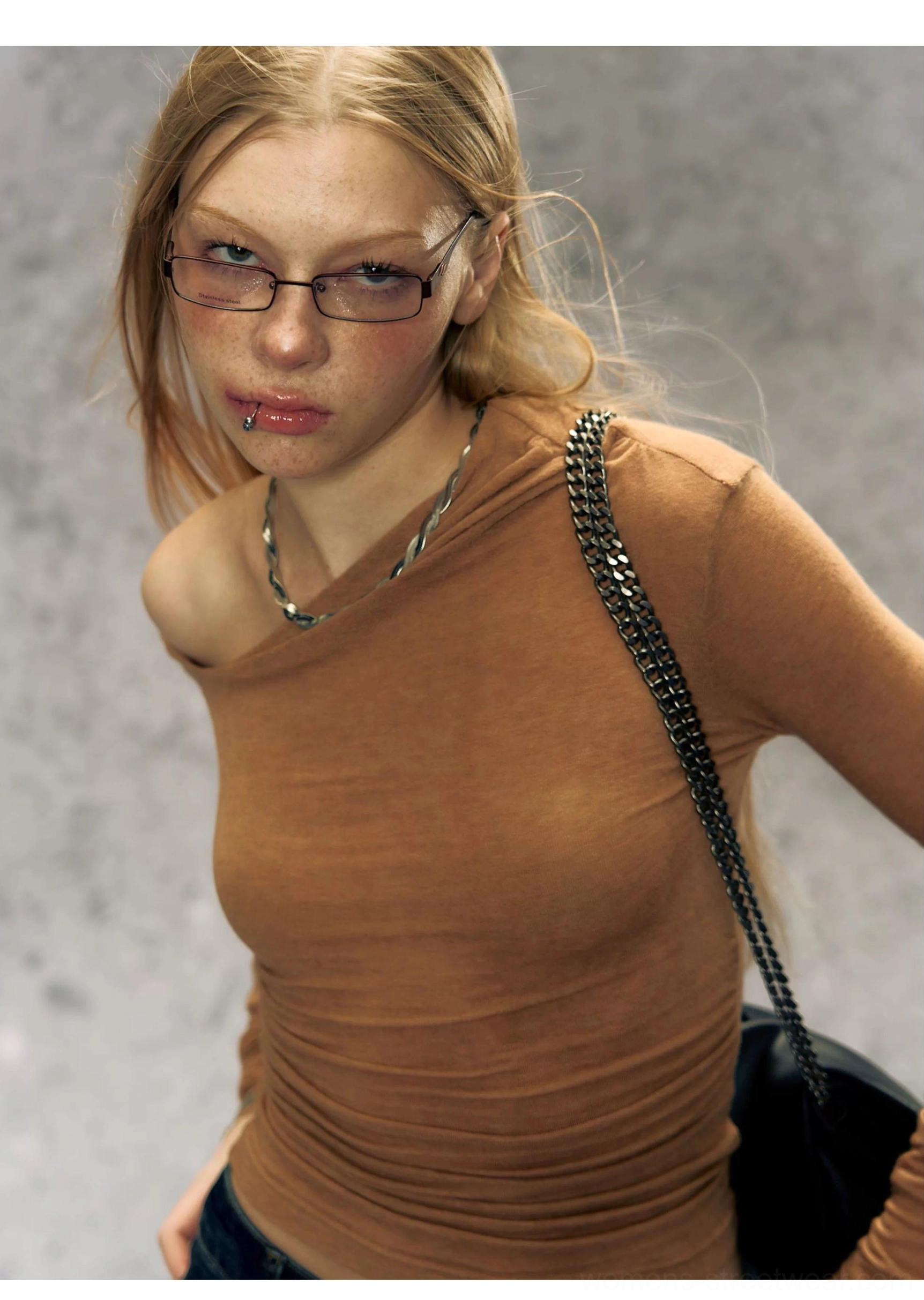 Close-up of caramel brown asymmetrical one-shoulder Korean streetwear top with layered necklaces and chain bag