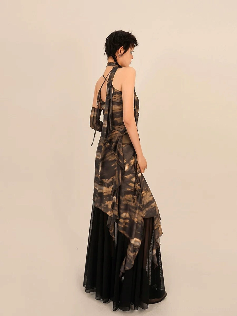Back view of a brown black tie dye two piece streetwear outfit showing the halter camisole tie and flowing asymmetrical maxi skirt silhouette