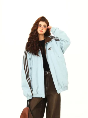 Blue reverse side of oversized reversible bomber jacket with black sleeve stripes and ribbed collar