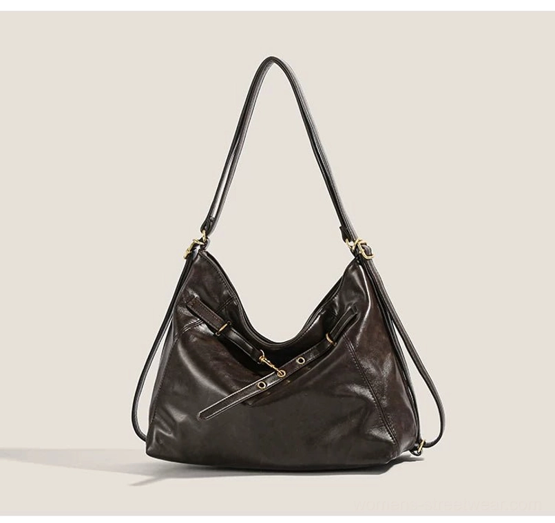 Brown vintage-inspired hobo shoulder bag shown from the front with adjustable straps, decorative buckle fastener details, and spacious everyday streetwear design