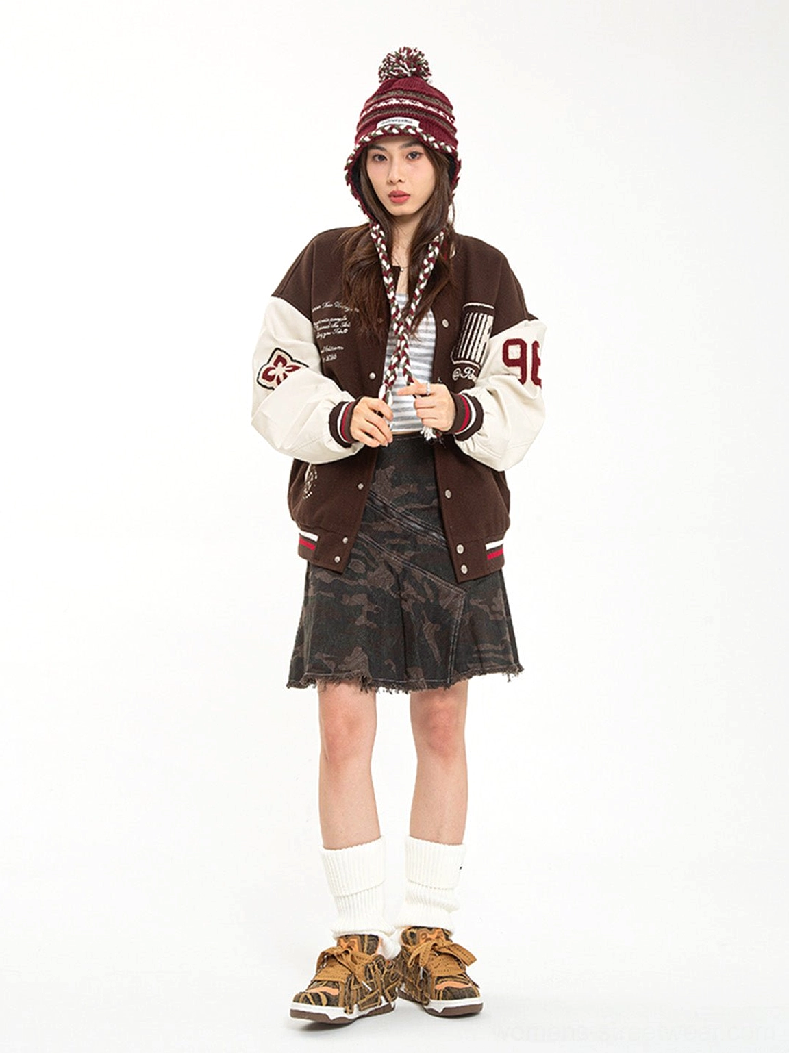Female model styling brown camo chunky platform skate sneakers with varsity jacket and camo mini skirt