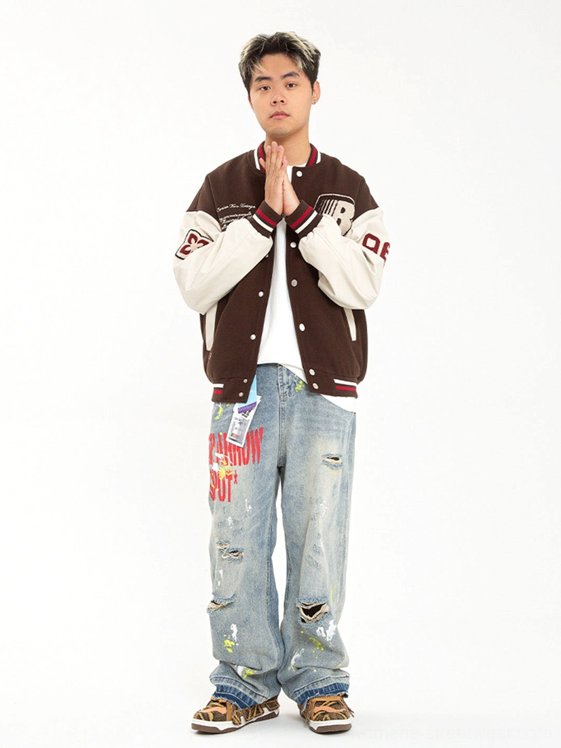 Male model wearing brown camo chunky platform skate sneakers with varsity jacket and distressed jeans