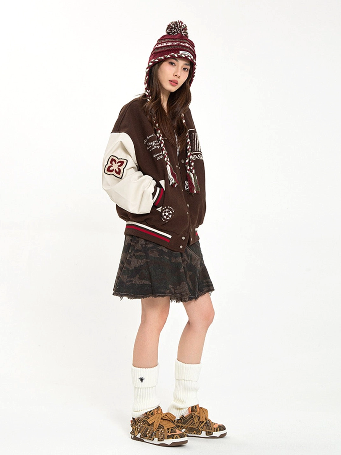 Female model wearing brown camouflage chunky skate sneakers with white crew socks and varsity streetwear
