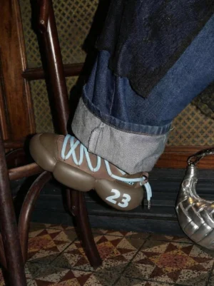 Brown chunky leather summer sneaker worn with rolled dark blue denim jeans, showing the sculpted split outsole and 23 heel mark