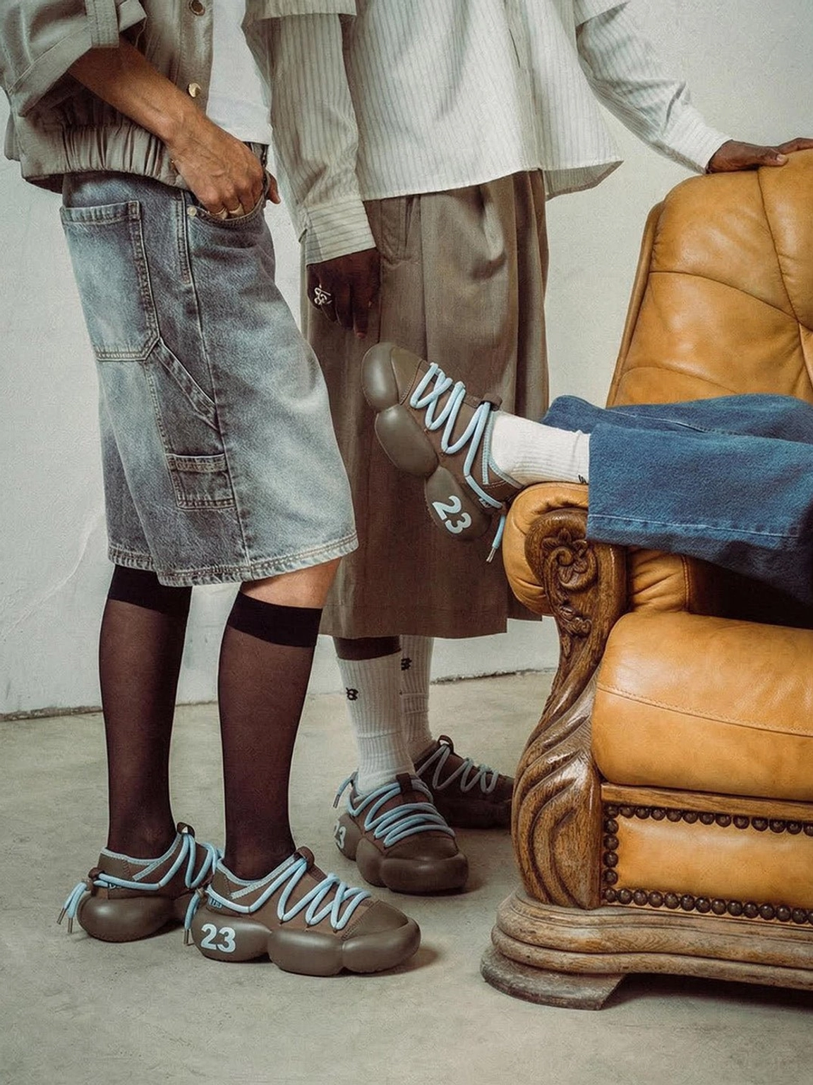 Two models wearing brown chunky leather summer sneakers with socks and denim outfits in a relaxed everyday streetwear setting