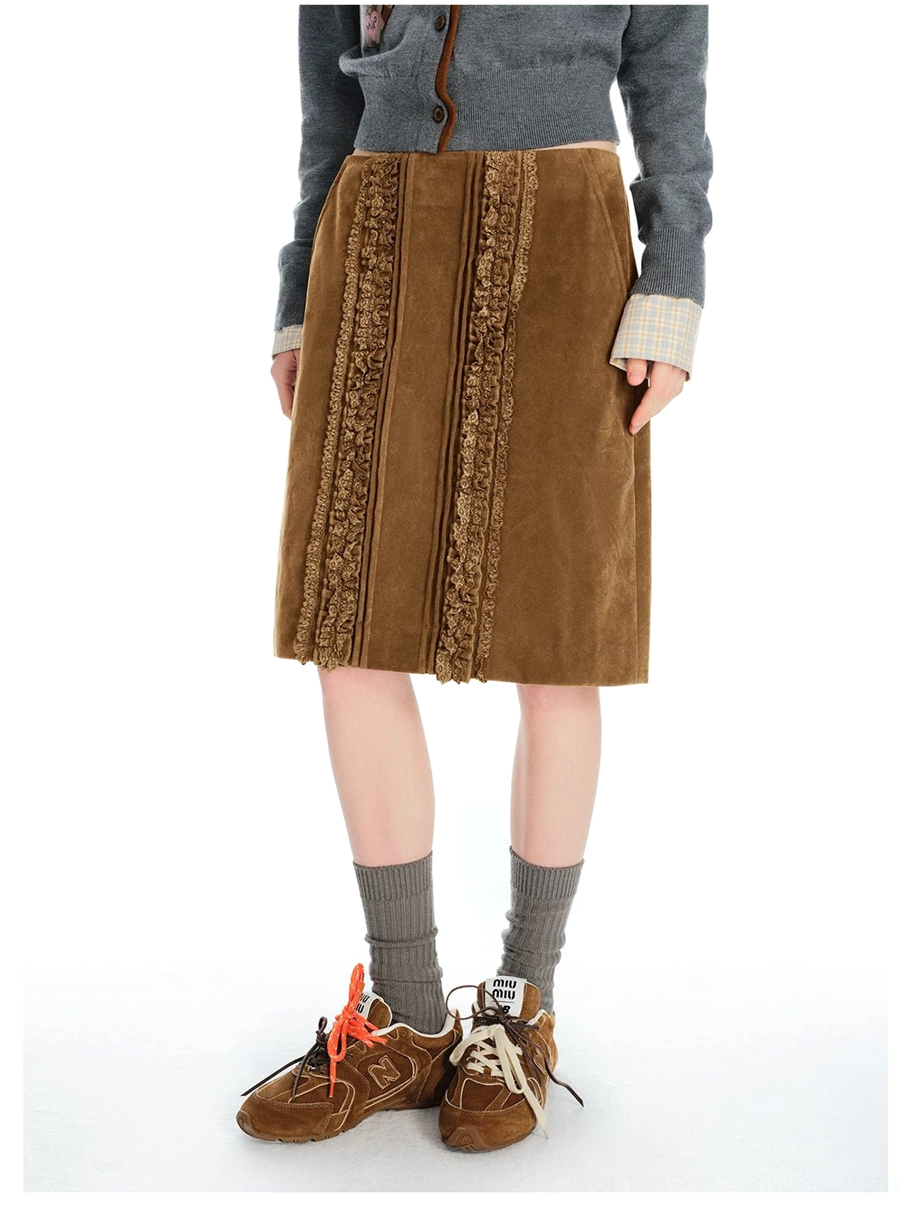 Waist-down view of a brown corduroy midi skirt with front lace trim styled with a cropped knit top socks and retro sneakers