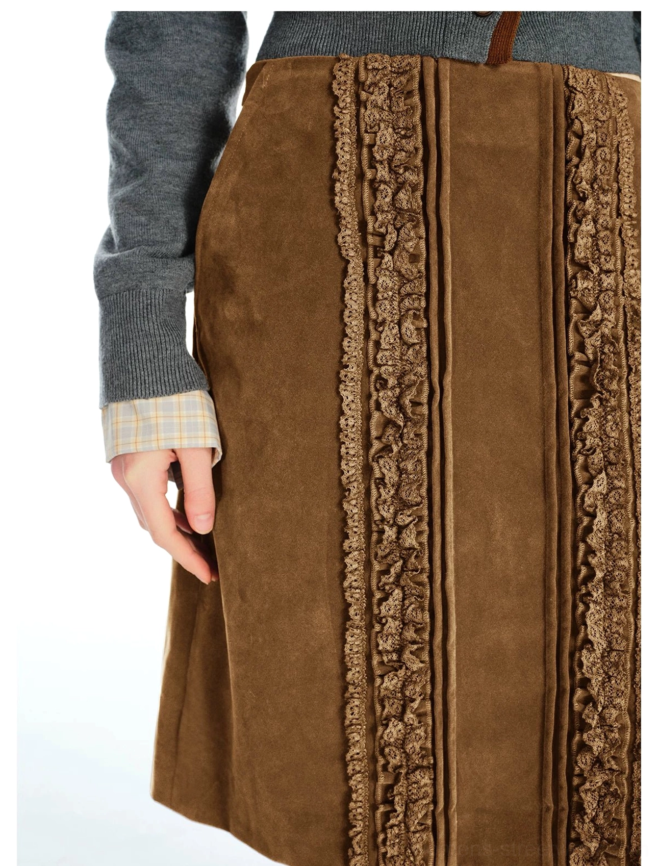 Close-up view of warm brown corduroy midi skirt fabric with vertical ruffled lace panels and decorative piping at the front