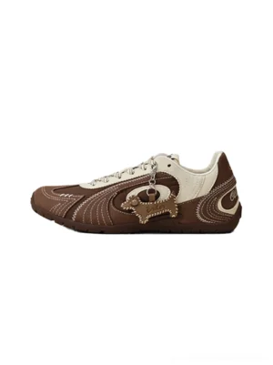 Brown and cream swirl panel retro trainers with dog-shaped side charm shown in a front-side flat lay
