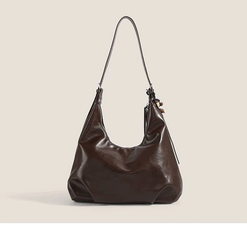 Minimalist brown crescent hobo shoulder bag shown from the front with soft faux leather and decorative leather tassel
