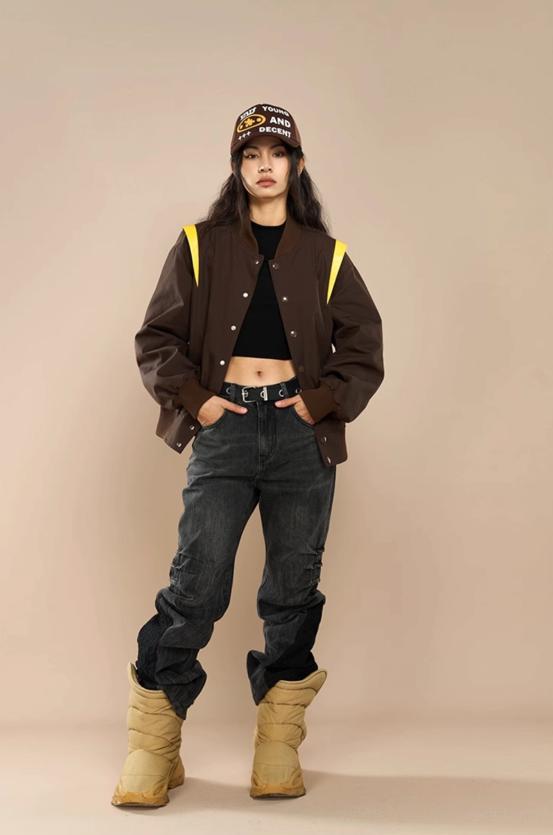 Female model wearing brown crown embroidered varsity baseball jacket with crop top baggy jeans and desert boots