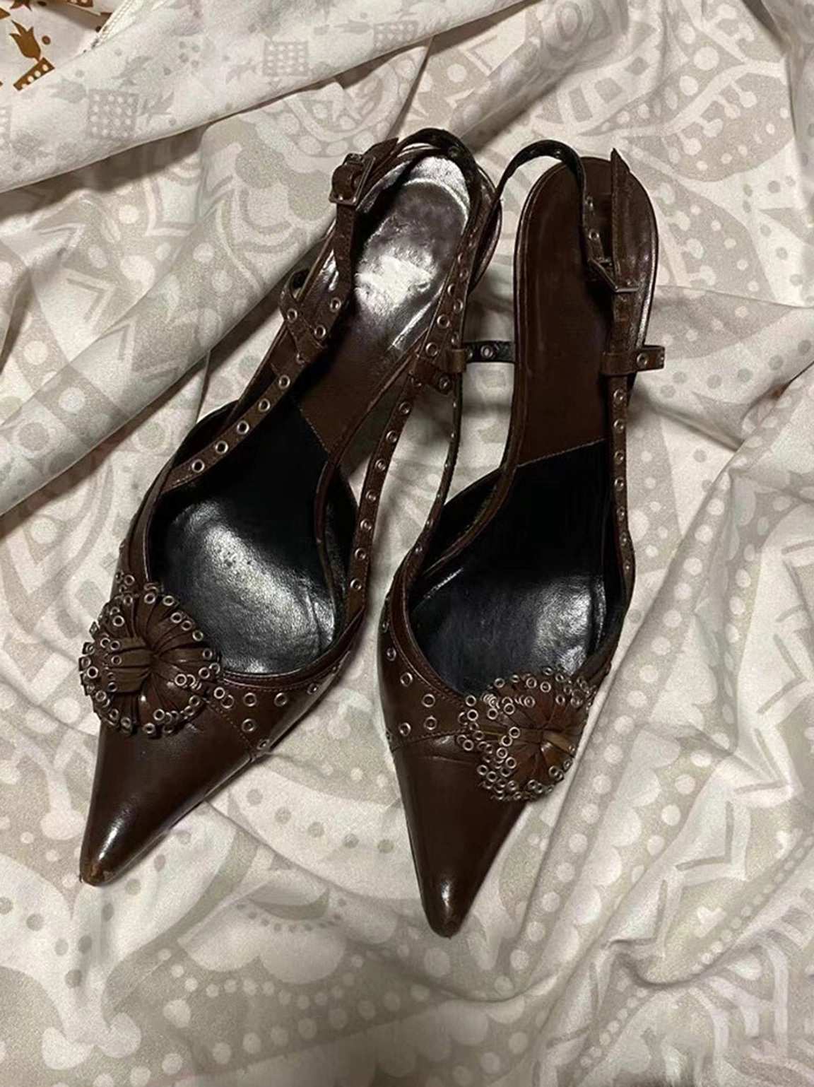 Brown crystal stud pointed slingback heels shown from a top-down view with flower-shaped vamp ornament, adjustable buckle strap, and 6 cm mid heel