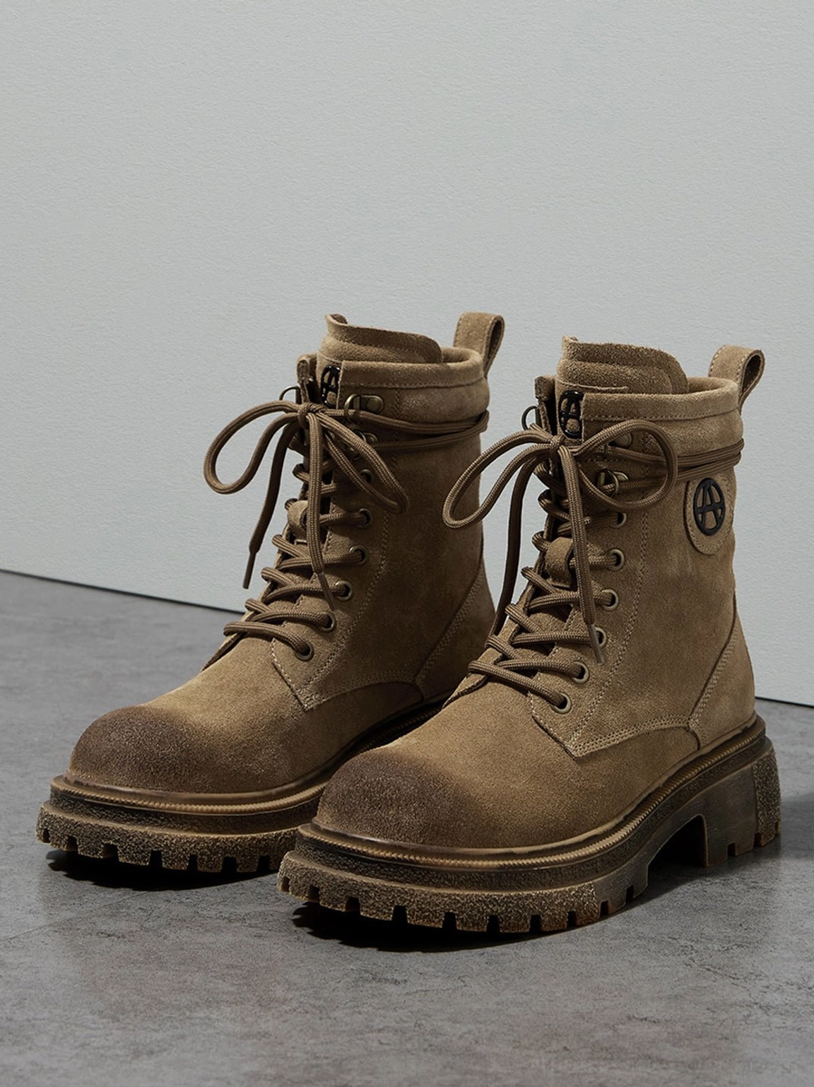 Pair of brown distressed combat boots neatly arranged front view on gray matte background full shoe appearance