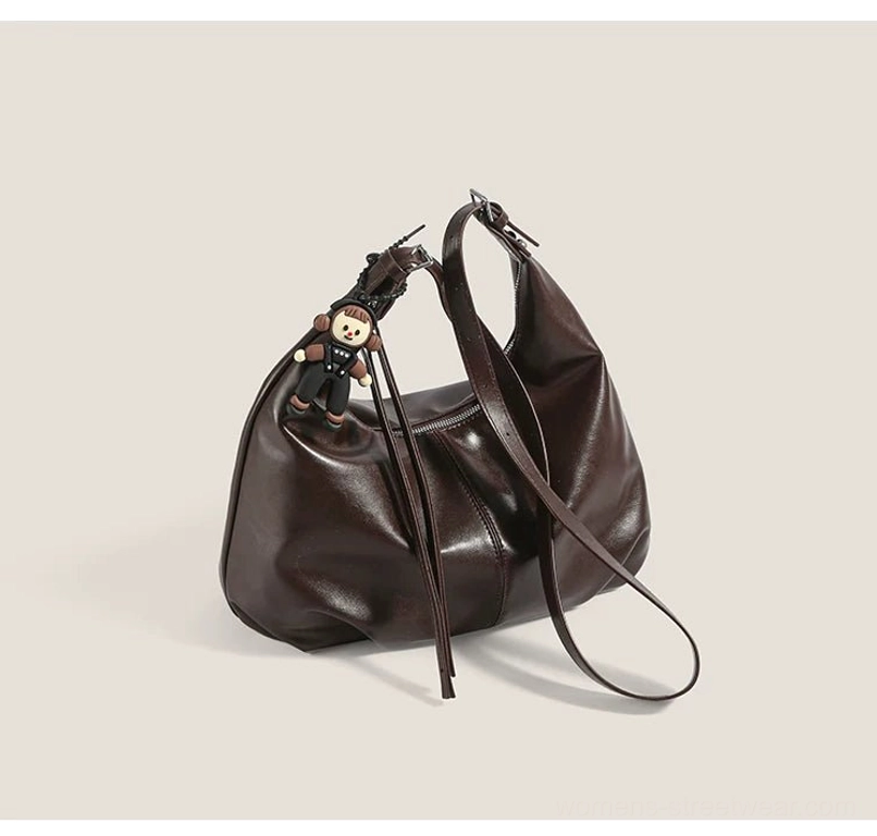 Top rear view of a brown faux-leather hobo bag showing the adjustable shoulder strap, monkey pendant, and slouchy shape