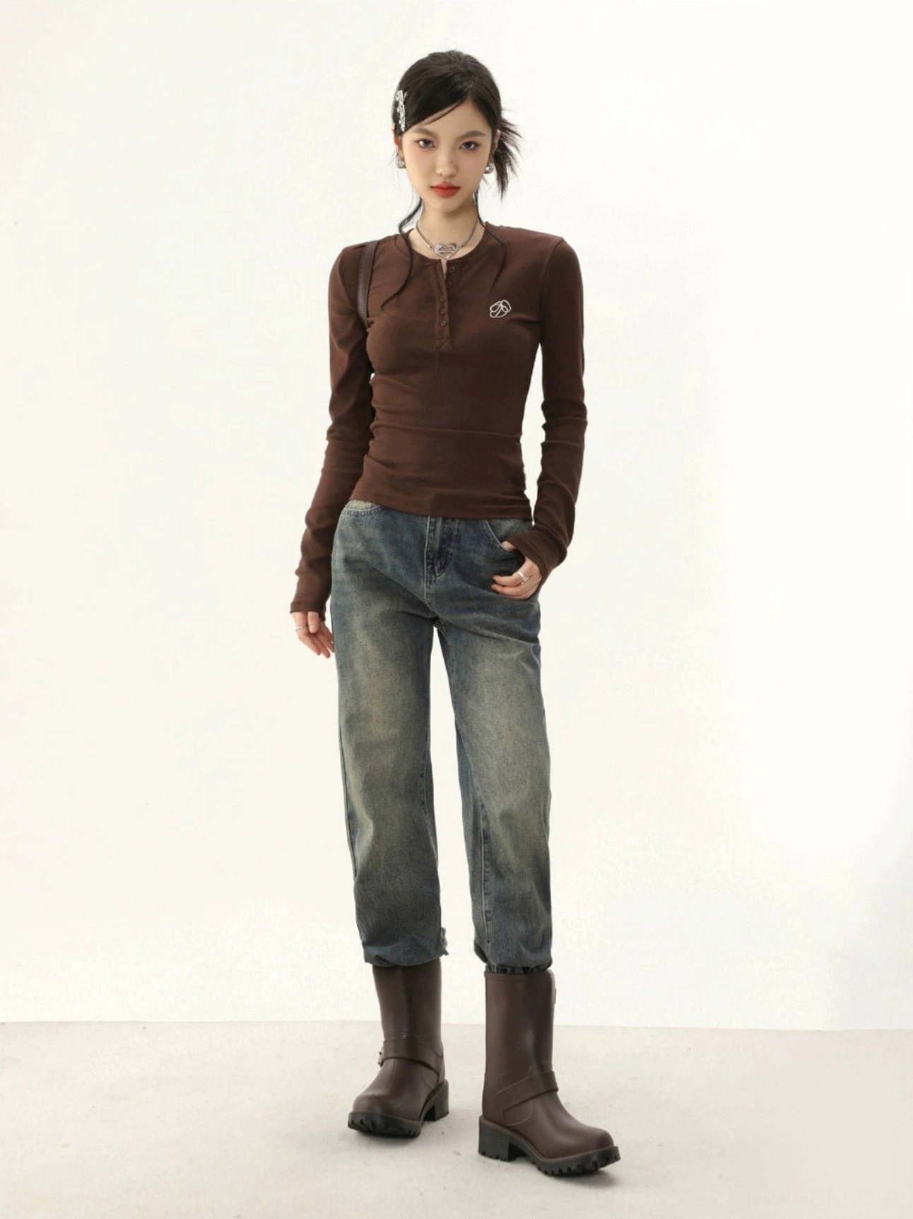 Brown fitted ribbed Henley long-sleeve top with small chest embroidery styled with vintage washed jeans and chunky brown ankle boots